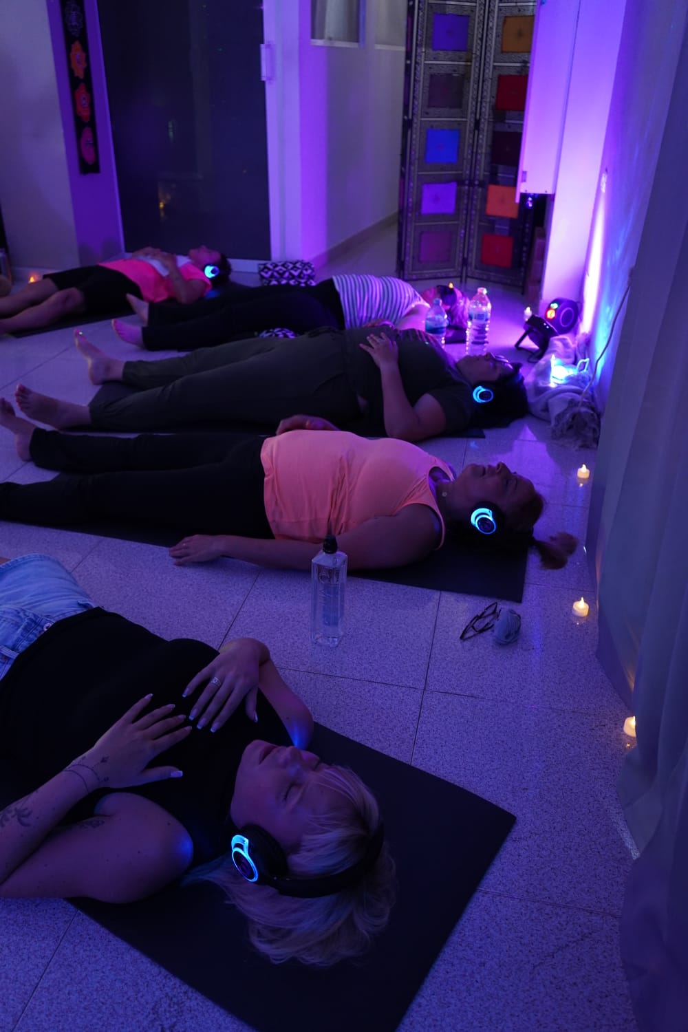 Participantes en sesi&oacute;n de Breathwork Canarias con auriculares LED bajo luz violeta